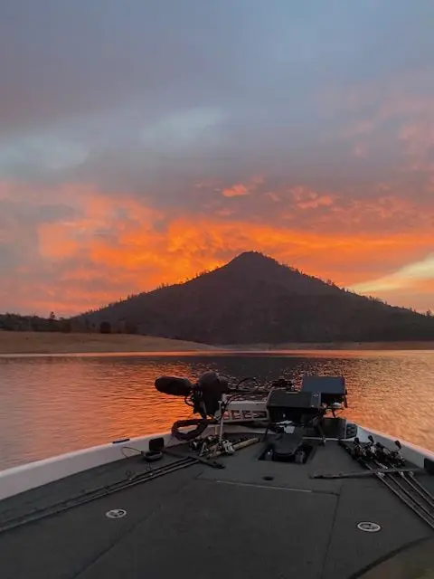 A boat is in the water at sunset.