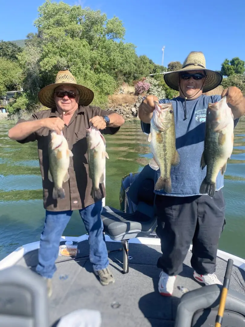 Two fishermen holding large bass.